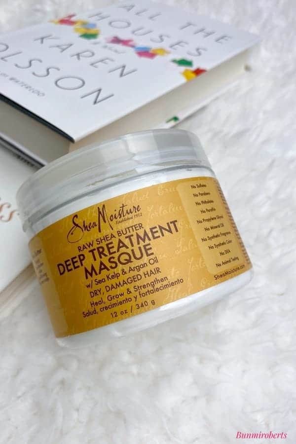 A picture with shea moisture deep treatment masque laying on a book
