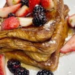 cinnamon French toast served with cut strawberries and blackberries and syrup