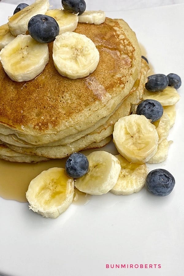 Banana pancake served with slice banana and blueberries and maple syrup