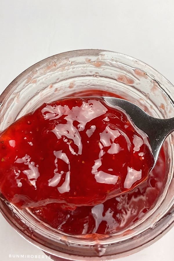 strawberry jam in a jar scooped with a spoon