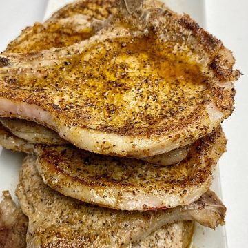 pan seared pork chops stacked on a plate