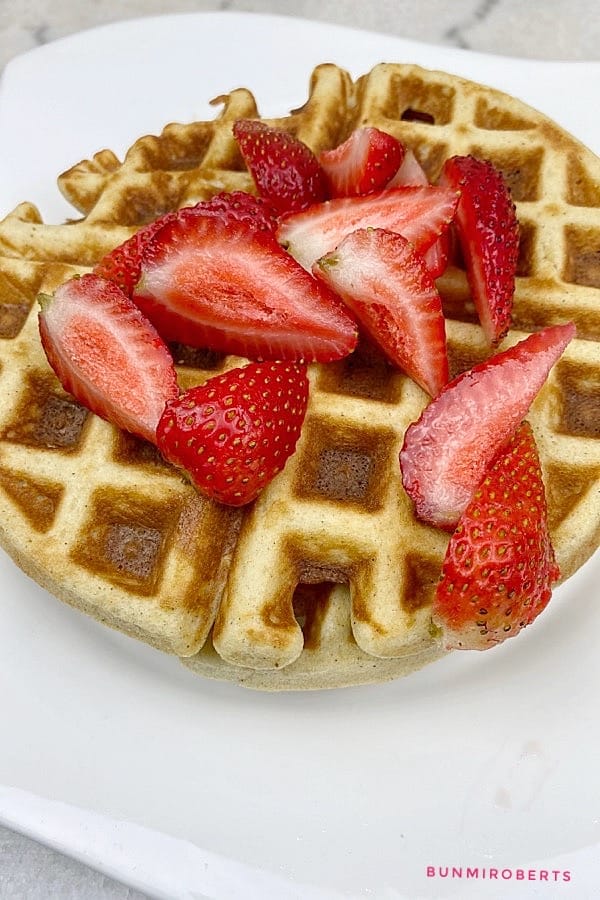 almond flour keto waffles served with cut strawberries and whipped cream