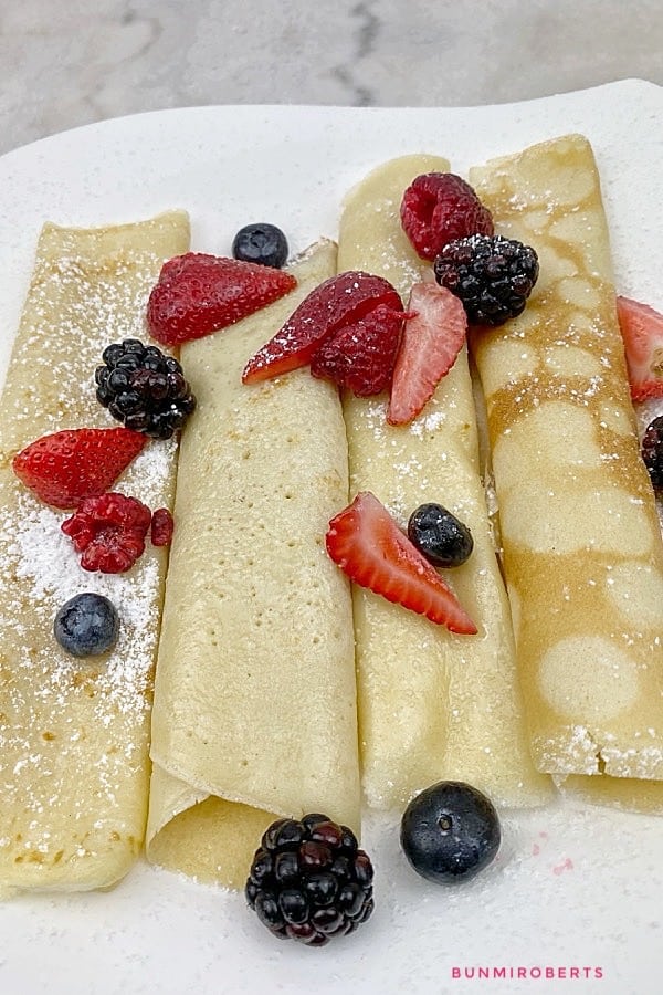Crepes folded in quarters served with strawberries, blueberries 