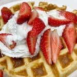 almond flour keto waffles served with cut strawberries and whipped cream